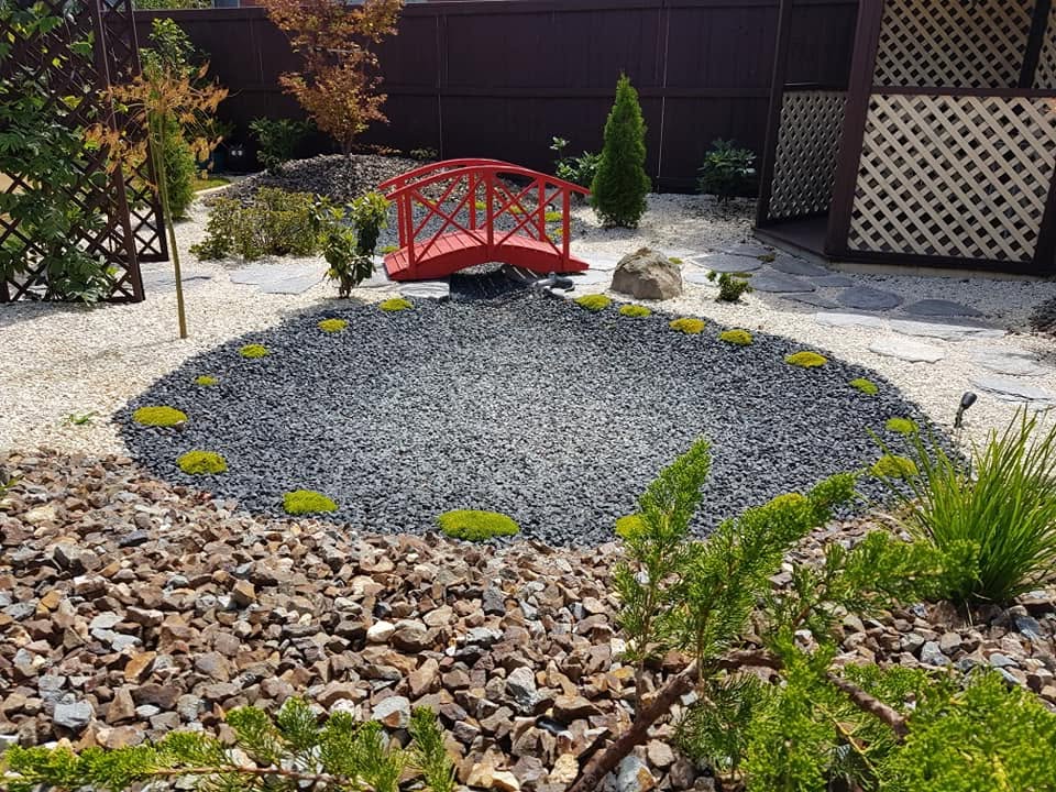 Japanese-influenced gravel garden with a red arched bridge, raked stone and clipped planting