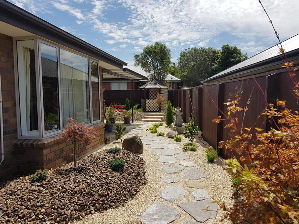 Home frontage with a natural stone path winding through gravel and mixed planting